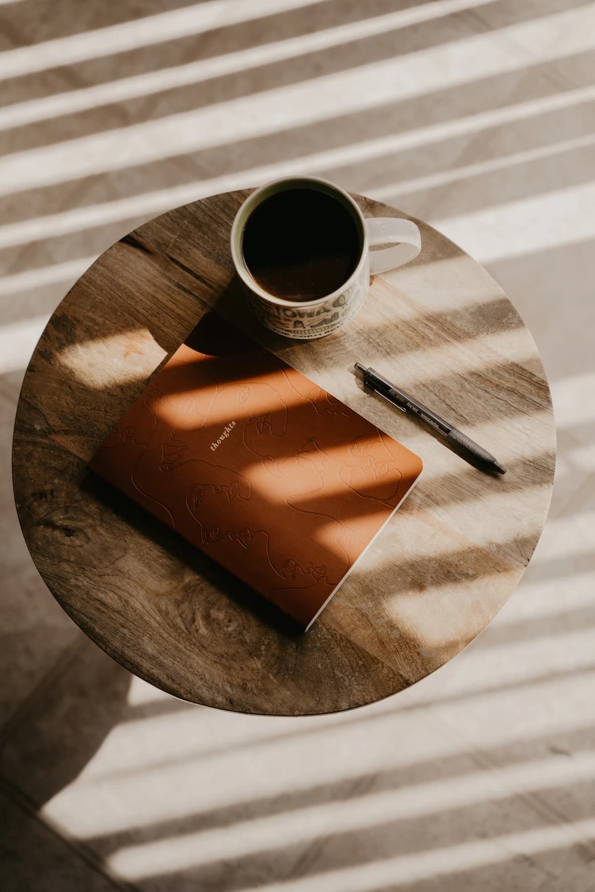 Coffee and a notebook in striped window light