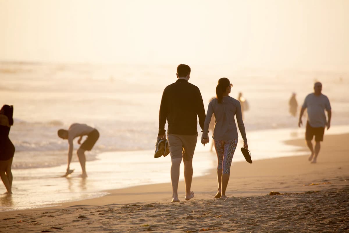A couple walking hand in hand along a golden beach